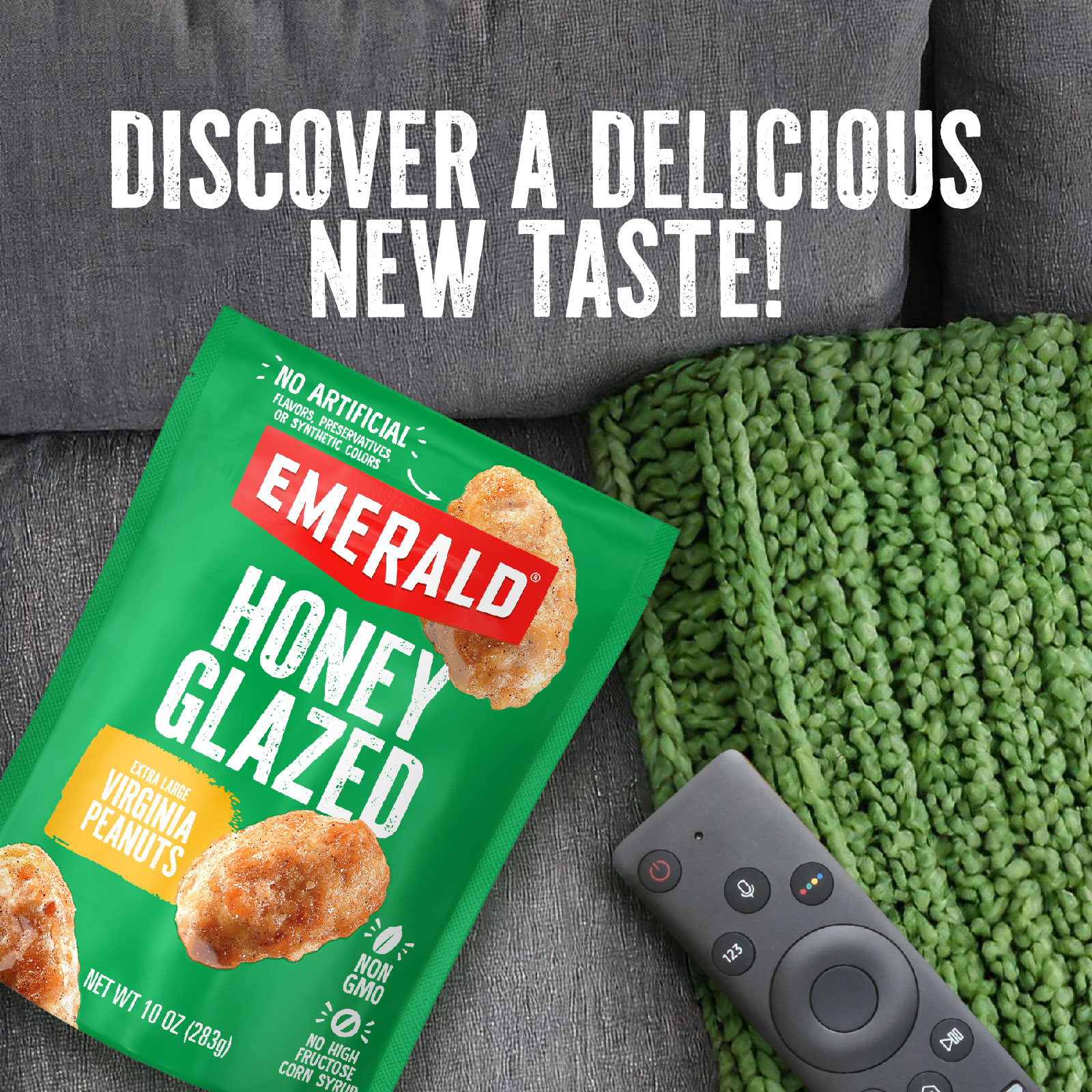 A bag of Emerald Honey Glazed Virginia Peanuts is on a gray couch next to a green knitted blanket. A black TV remote rests nearby. The text above reads, DISCOVER A DELICIOUS NEW TASTE!.